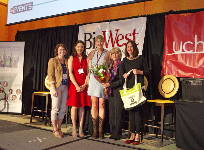 A group of women with flowers and gift bags on stage