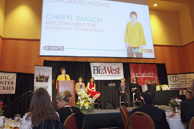 A congratulations slide on the screen as a speaker stands at the podium