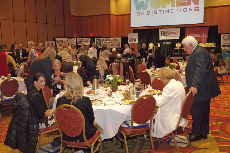 Guests leaving their tables beneath the Women of Distinction screen