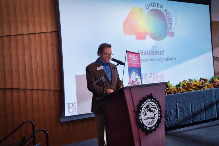 A speaker at the podium in front of the 40 Under Forty welcome screen