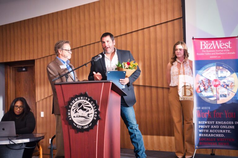 A man speaking at the podium holding flowers