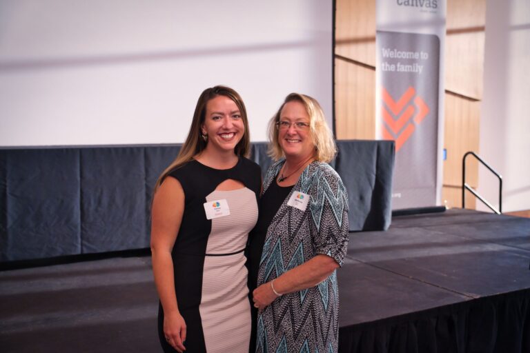 Two women posing beside the stage