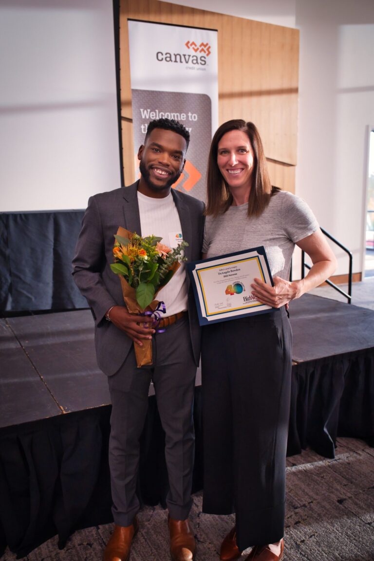 An honoree with flowers and a certificate beside a woman