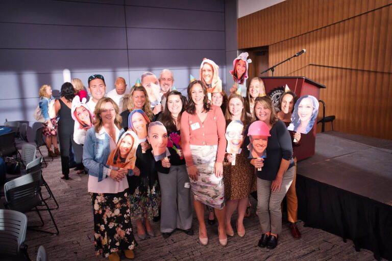 A group holding up cut-out face photos