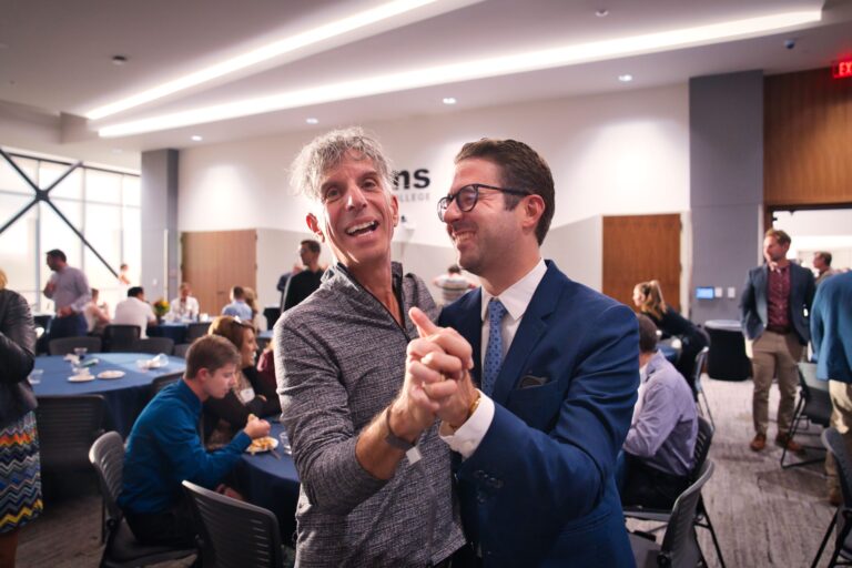 Two men clasping hands and smiling in the hall