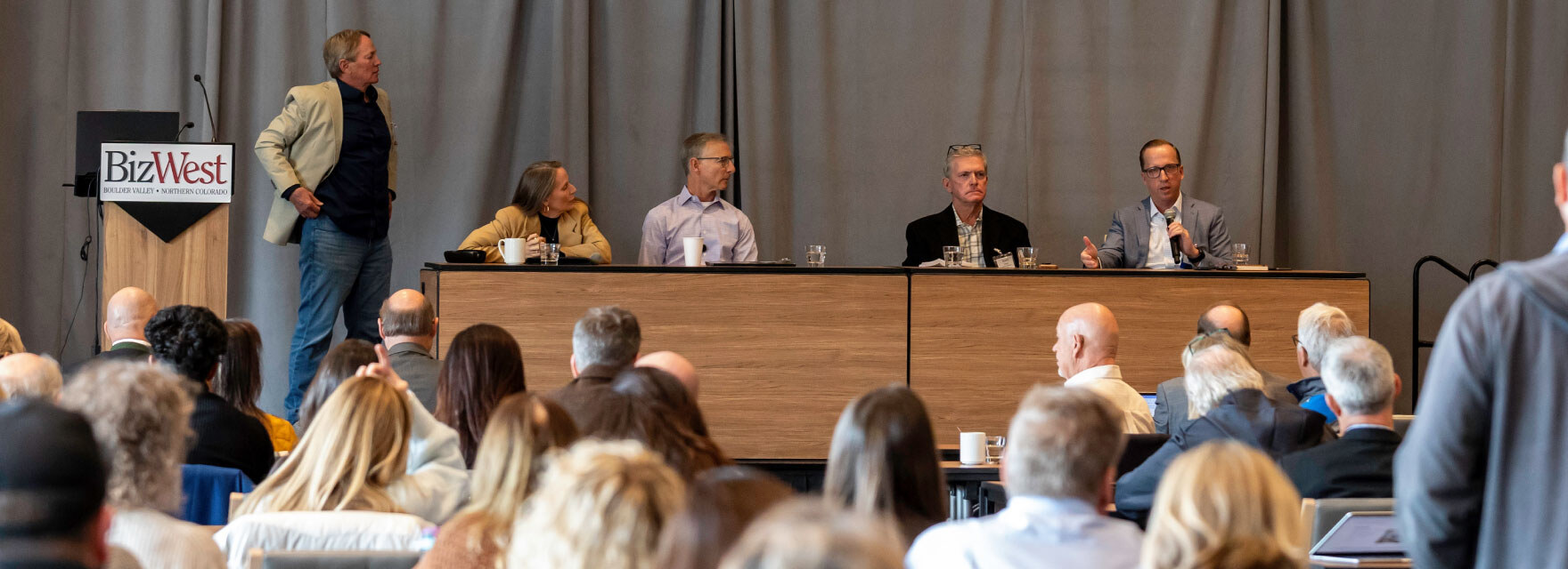 A panel of speakers addresses a full room at a BizWest summit