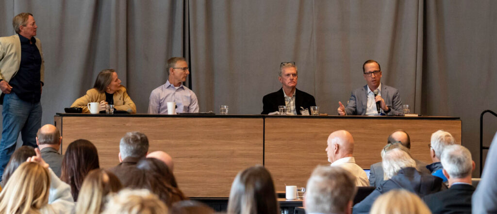Panelists in conversation in front of a full room at a BizWest summit