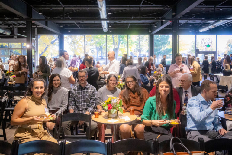 Guests seated at tables smiling toward the camera