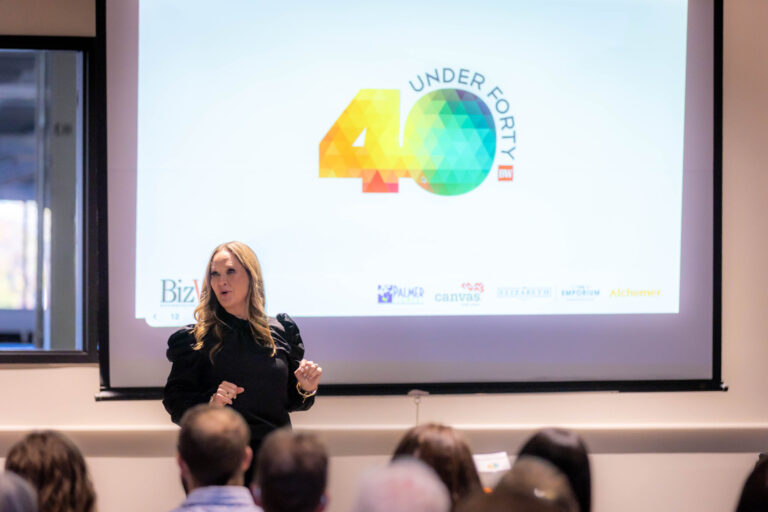 A speaker on stage in front of the 40 Under Forty logo on screen