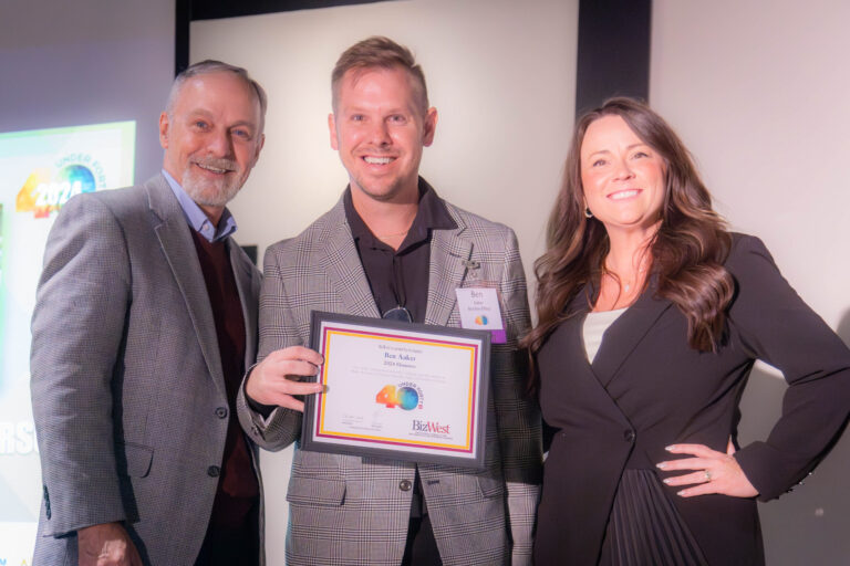 An honoree holding a certificate between two presenters