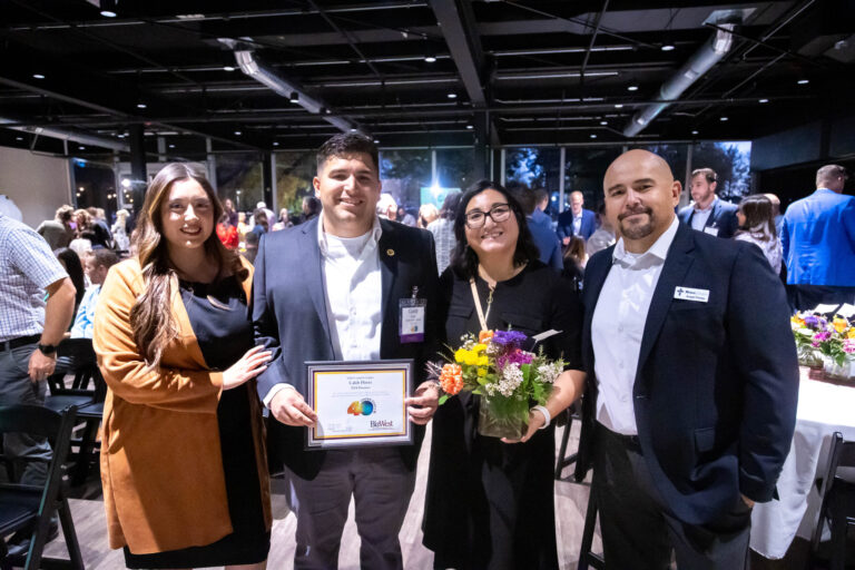 Four guests posing with a certificate and flowers