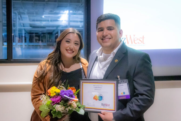 A woman with flowers and a man holding a certificate