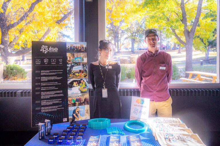 Two people at a Pulse sponsor table by the windows