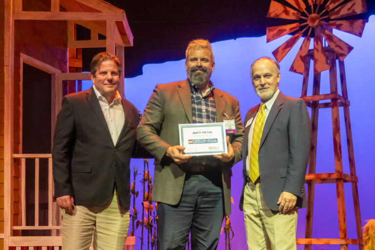 Three honorees on stage with an award at the 2025 event