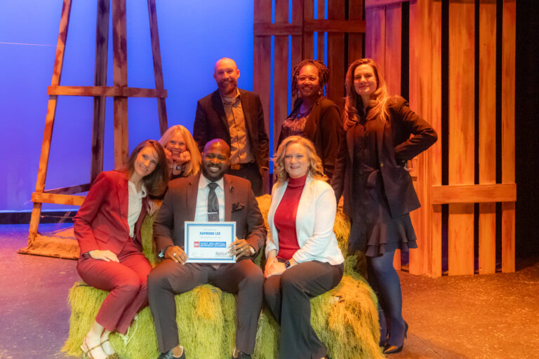 Honorees with their awards seated on hay bales on the stage set at the 2025 event