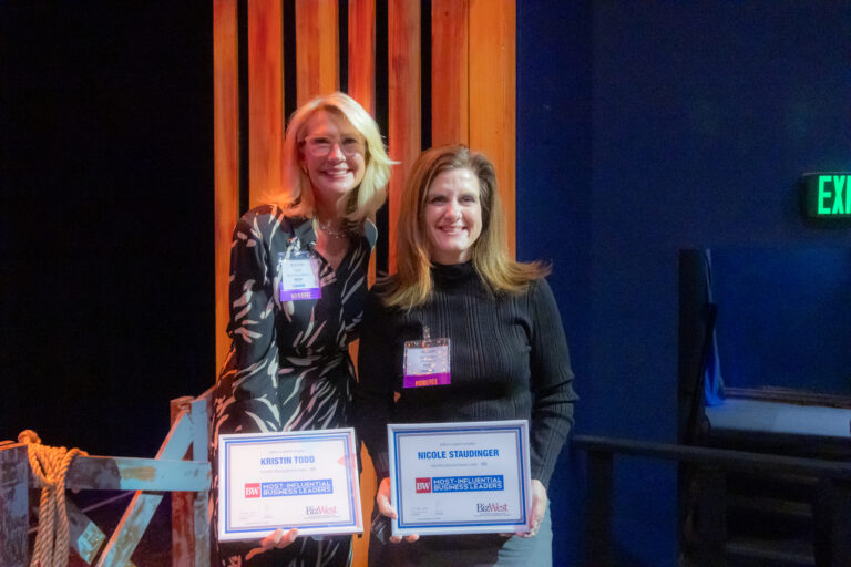 Two honorees hold their awards on stage at the 2025 event