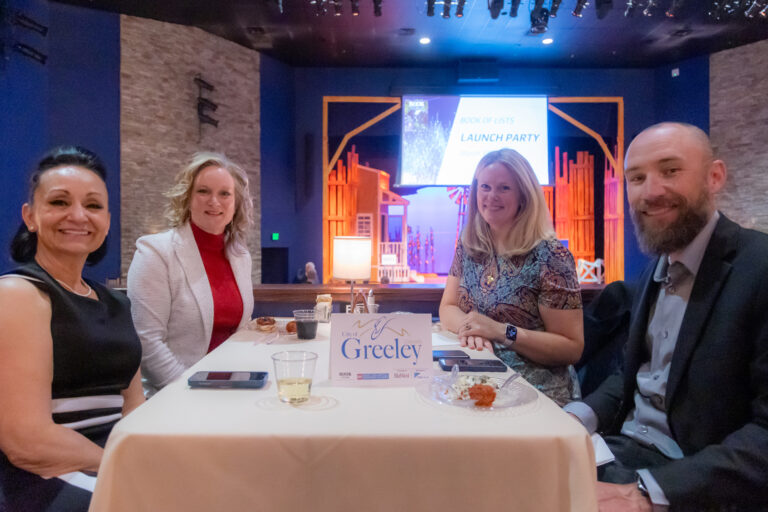 Guests seated at a table with a City of Greeley sign at the 2025 event