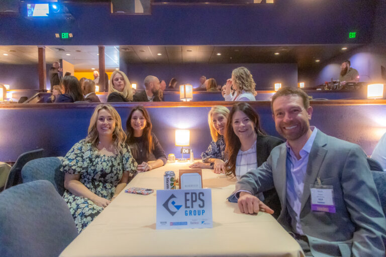 Guests seated at a table with an EPS Group sign at the 2025 event