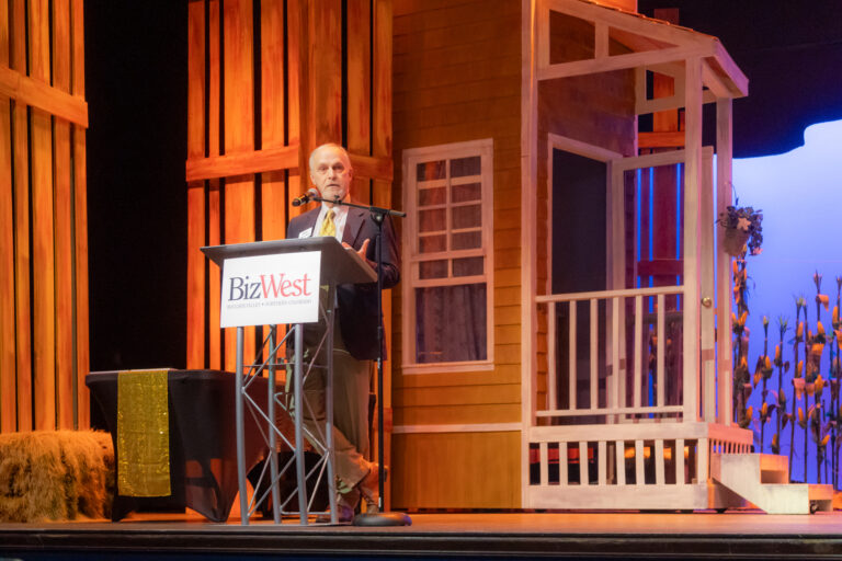 A speaker at the BizWest podium on stage at the 2025 Most-Influential Business Leaders event