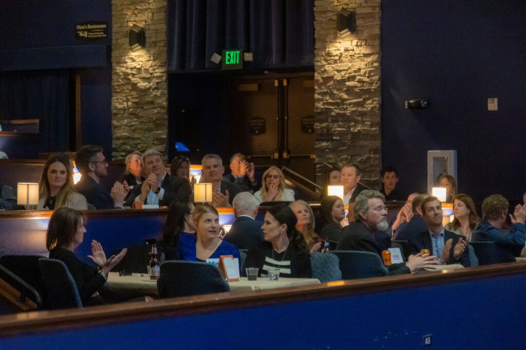 Attendees seated at tables applauding during the 2025 Most-Influential Business Leaders program (March 10, 2025, Candlelight Dinner Theater)