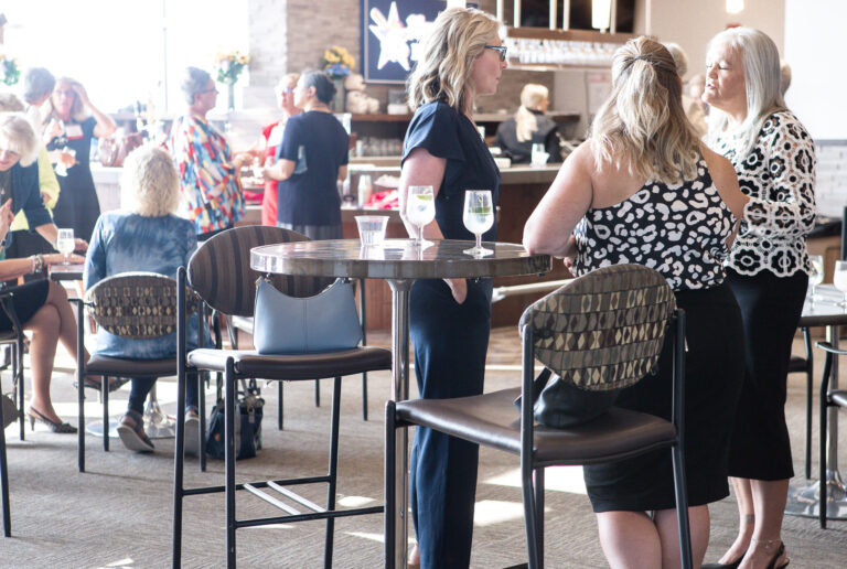 Guests talking around high-top tables at the reception
