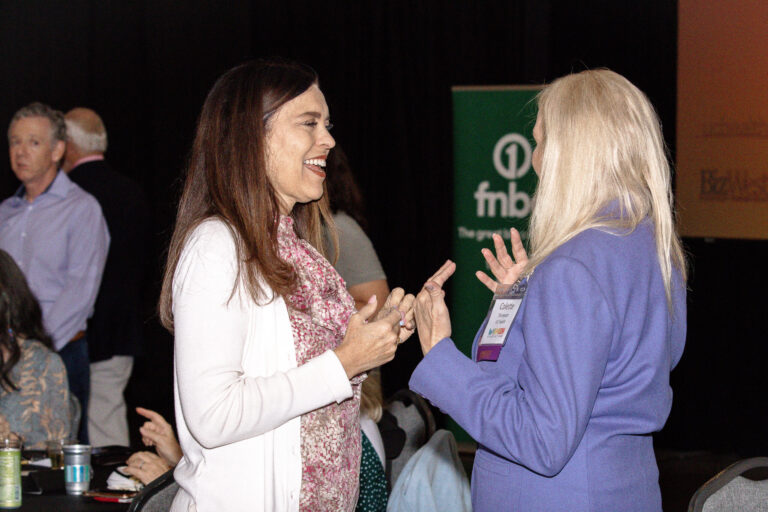 Two guests talking in front of an FNBO banner