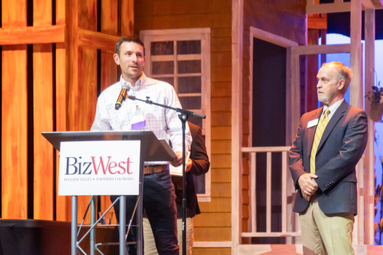 Two speakers at the BizWest podium during the 2025 program