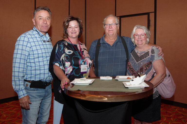 Four guests posing beside a cocktail table at the reception