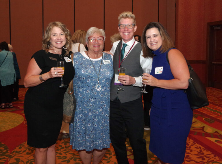 Four guests posing together with drinks