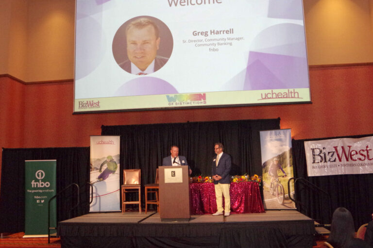 The stage with a welcome slide on the screen and the BizWest banner