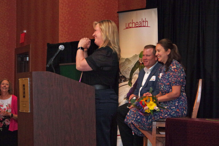 A speaker holding a microphone at the podium