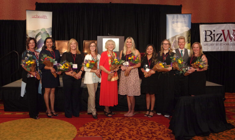 A row of women holding flowers on stage
