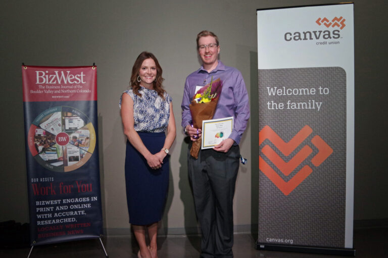 An honoree holding flowers and a certificate beside a presenter