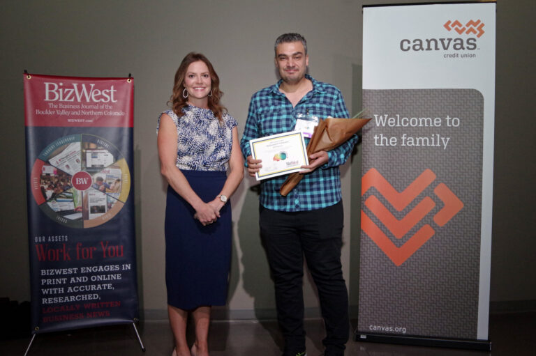 An honoree in a plaid shirt holding a certificate beside a presenter