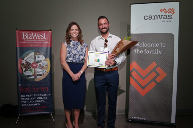 An honoree holding a certificate and flowers beside a presenter