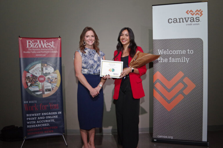 An honoree in a red blazer holding a certificate beside a presenter