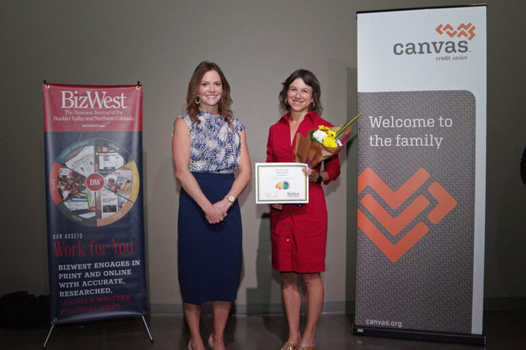 An honoree in a red dress holding a certificate beside a presenter