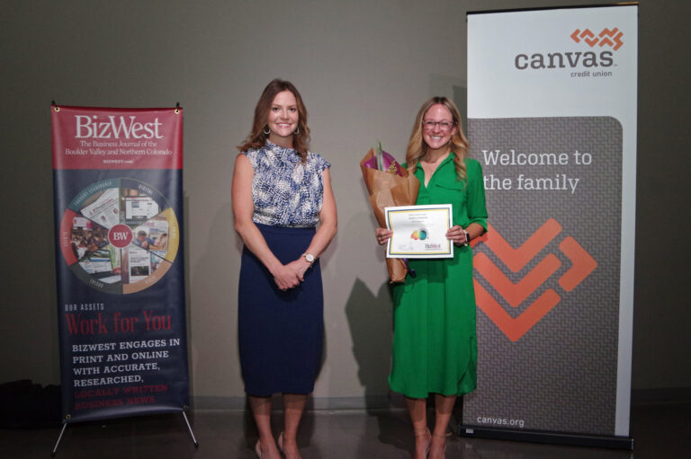 An honoree in a green dress holding a certificate beside a presenter