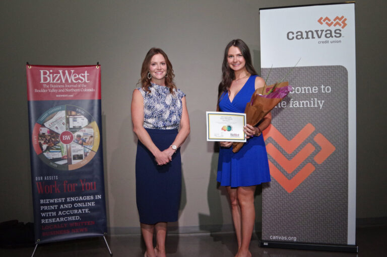 An honoree in a blue dress holding a certificate beside a presenter