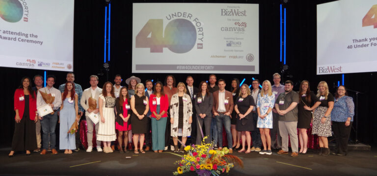 A large group on stage beneath the 40 Under Forty screen