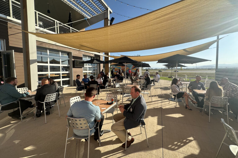Guests at tables on a shaded patio