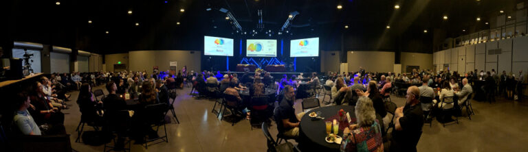 A wide view of the hall with screens lit above the stage